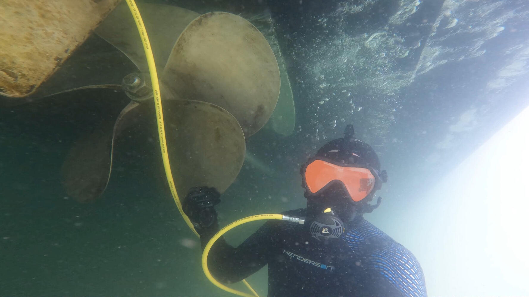 diver cleaning boat hull and propeller diver cleans propeller of large sailboat in Marina del Rey, California